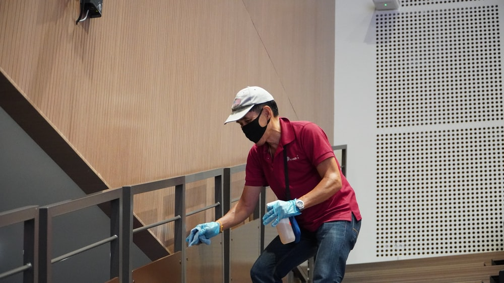 A person holding a spray and cleaning glass deck railings 