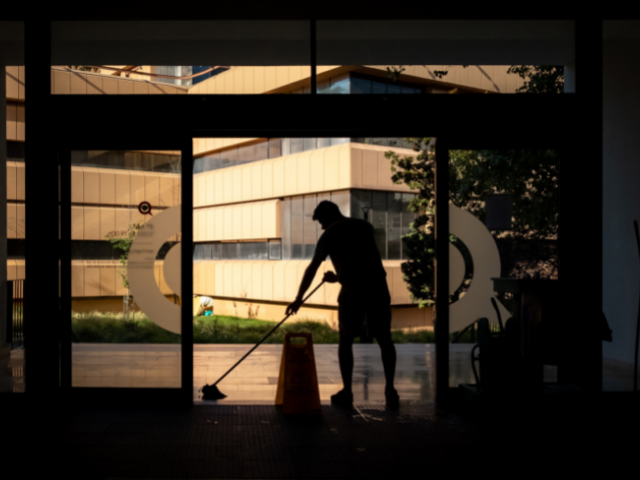 A person mopping the entrance of a workspace